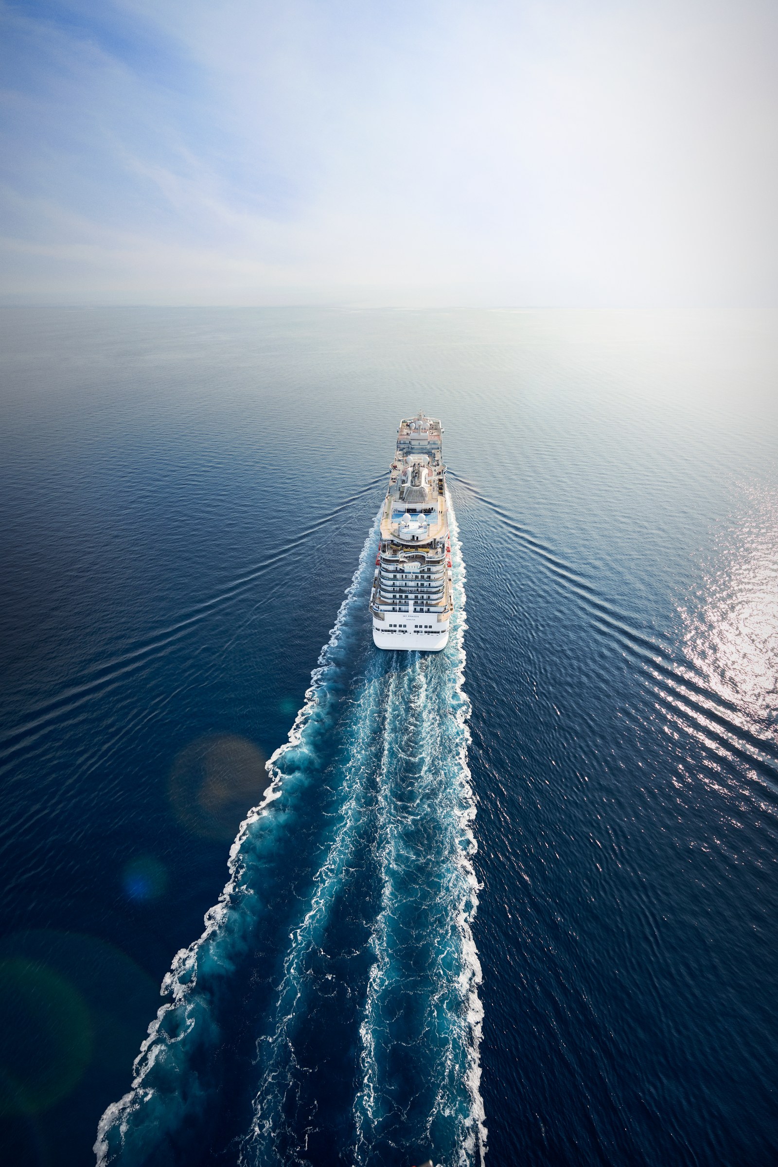 Overhead aerial of Sky Princess at sea with its white wake trailing behind