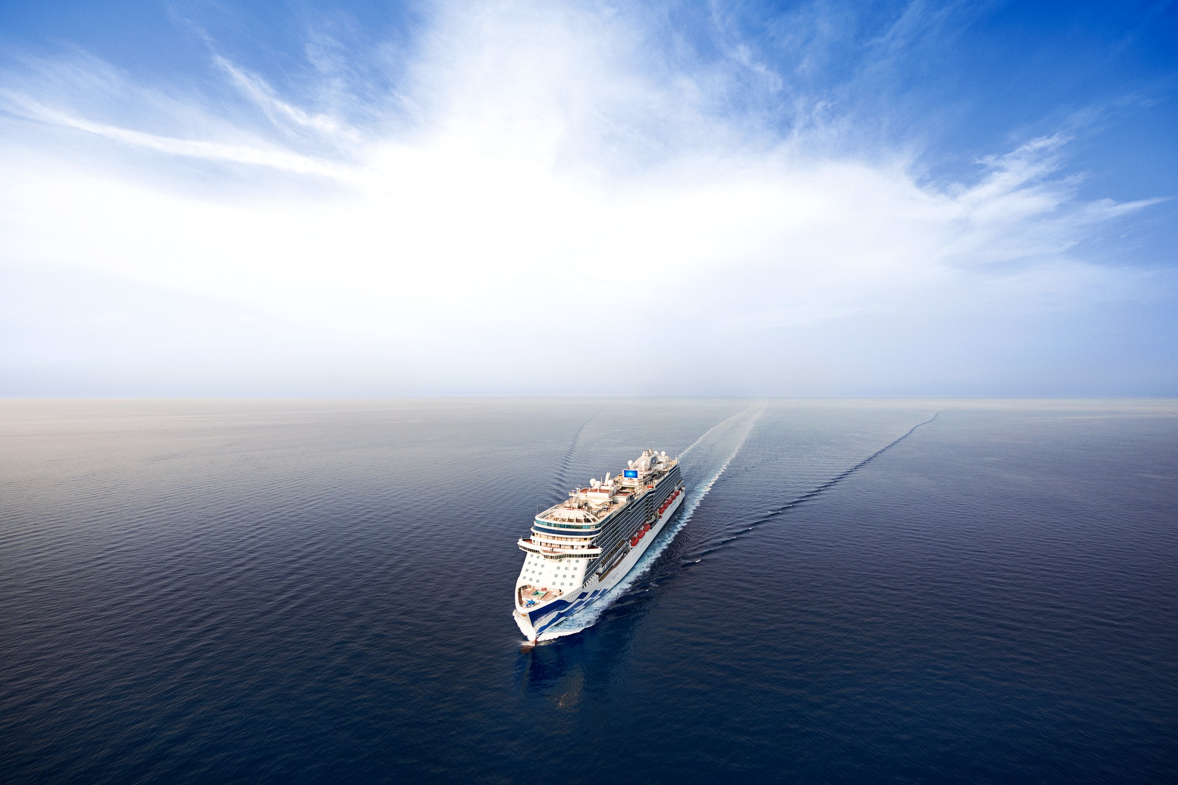 Sky Princess sailing toward the camera on a calm open sea under a bright sky