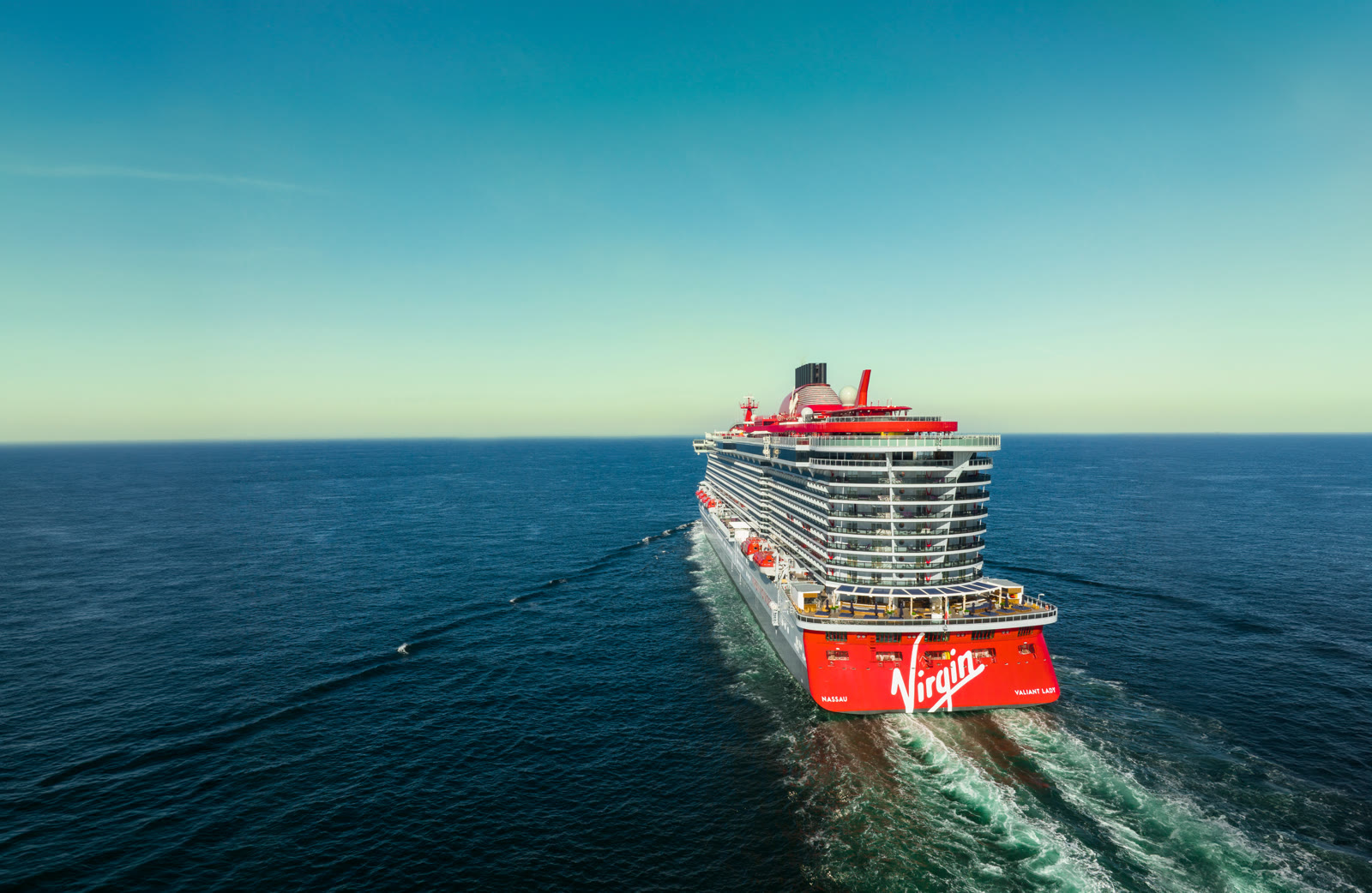 Valiant Lady under way on blue ocean, red stern with Virgin logo visible
